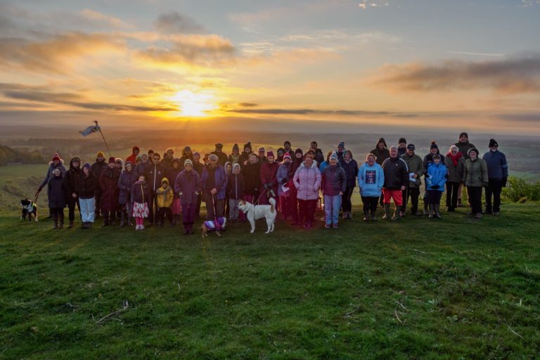 Group of people on a hill, with sunrise behind - celebrating Easter